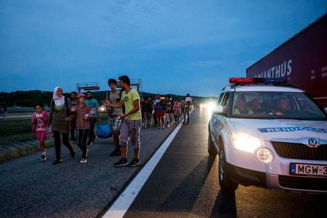 Biatorbágy, 2015. szeptember 4. Rendõri kíséret mellett illegális bevándorlók gyalogolnak az M1-es autópályán Biatorbágy közelében Ausztria felé 2015. szeptember 4-én. A központi operatív törzs úgy döntött, hogy az éjszaka folyamán autóbuszokat vezényel a Keleti pályaudvarhoz és a M1-es autópályához, és felajánlják az ott tartózkodó bevándorlóknak, hogy a hegyeshalmi határátlépési ponthoz szállítják õket. MTI Fotó: Bodnár Boglárka